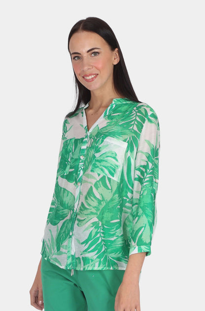 Woman wearing green and white tropical print blouse